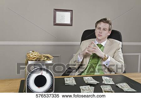 Businessman sitting in front of currency notes with gold jewelry on a weight scale View Large Photo Image Stock Photography - Businessman sitting in front of currency notes with gold jewelry on a weight scale. Fotosearch