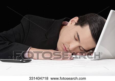 Businessman sleeping next to laptop View Large Photo Image Stock Photo - Businessman sleeping next to laptop. Fotosearch