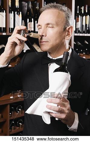Businessman smelling cork of a wine bottle View Large Photo Image Stock Photo - Businessman smelling cork of a wine bottle. Fotosearch
