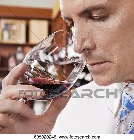 Stock Photograph - Businessman smelling red wine in a bar. Fotosearch