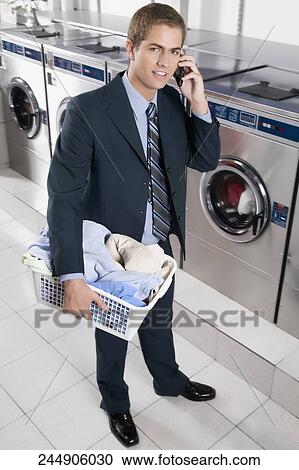 Businessman talking on a mobile phone in a laundromat View Large Photo Image Stock Image - Businessman talking on a mobile phone in a laundromat. Fotosearch