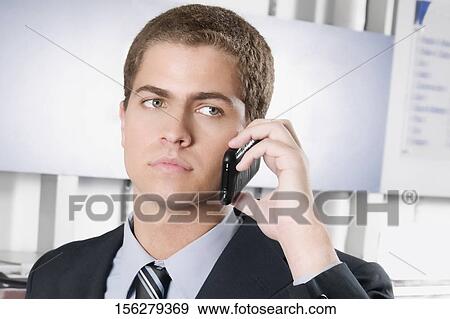 Businessman talking on a mobile phone in a laundromat View Large Photo Image Stock Photo - Businessman talking on a mobile phone in a laundromat. Fotosearch