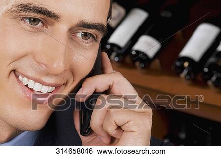 Businessman talking on a mobile phone in a bar View Large Photo Image Stock Photograph - Businessman talking on a mobile phone in a bar. Fotosearch
