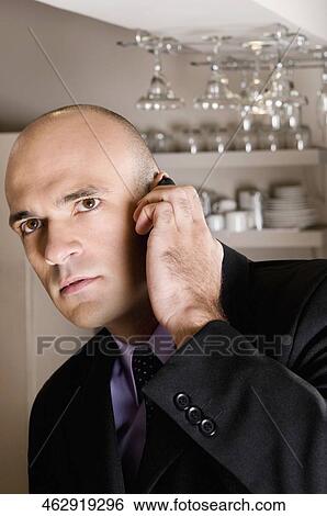 Businessman talking on a mobile phone in a bar View Large Photo Image Stock Photograph - Businessman talking on a mobile phone in a bar. Fotosearch