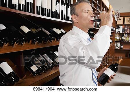 Businessman tasting wine in a cellar View Large Photo Image Picture - Businessman tasting wine in a cellar. Fotosearch