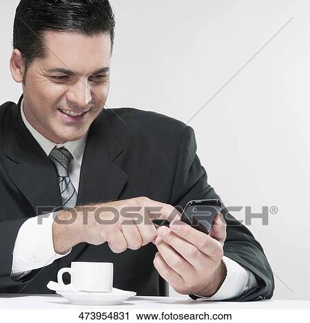 Stock Image - Businessman text messaging on a mobile phone. Fotosearch