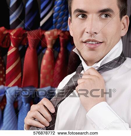 Stock Image - Businessman trying on a tie in a clothing store. Fotosearch