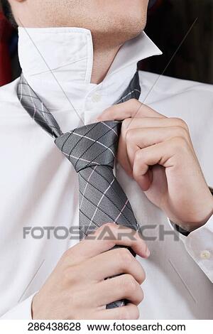 Stock Photo - Businessman trying on a tie in a clothing store. Fotosearch