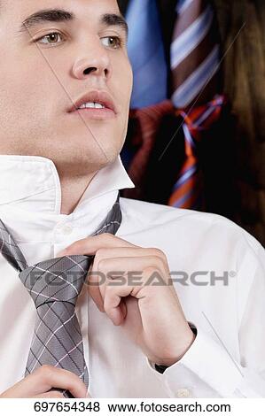 Businessman trying on a tie in a clothing store View Large Photo Image Stock Photo - Businessman trying on a tie in a clothing store. Fotosearch