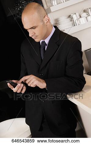 Businessman using a mobile phone in a bar View Large Photo Image Stock Photo - Businessman using a mobile phone in a bar. Fotosearch