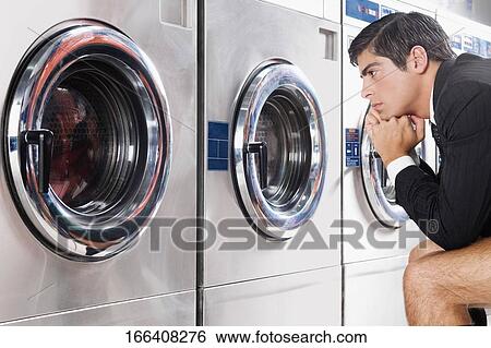Stock Photograph - Businessman waiting in a laundromat. Fotosearch
