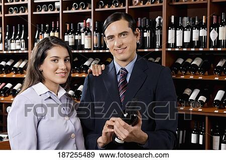 Stock Photo - Businessman with a businesswoman holding a wine bottle. Fotosearch