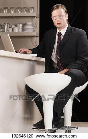 Stock Image - Businessman working on a laptop in a bar. Fotosearch