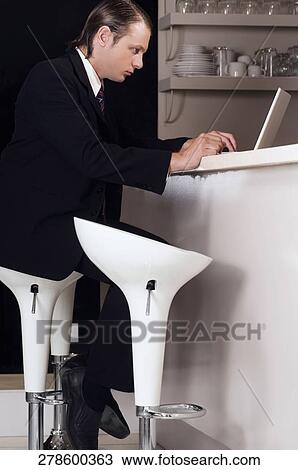 Stock Image - Businessman working on a laptop in a bar. Fotosearch
