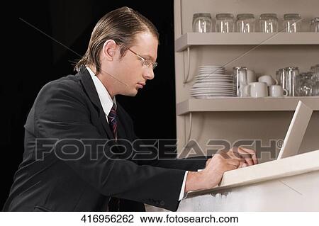 Stock Image - Businessman working on a laptop in a bar. Fotosearch