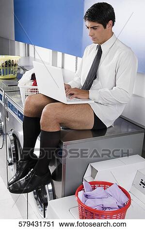Businessman working on a laptop in a laundromat View Large Photo Image Stock Image - Businessman working on a laptop in a laundromat. Fotosearch