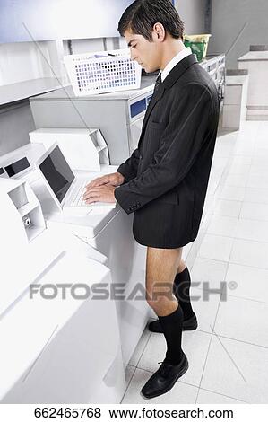 Businessman working on a laptop in a laundromat View Large Photo Image Stock Photo - Businessman working on a laptop in a laundromat. Fotosearch