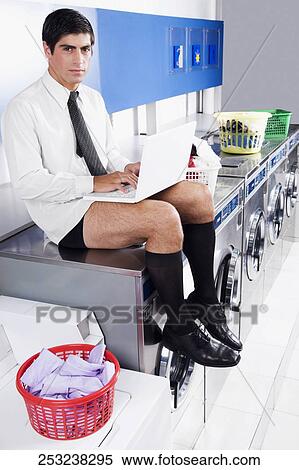 Businessman working on a laptop in a laundromat View Large Photo Image Stock Photography - Businessman working on a laptop in a laundromat. Fotosearch