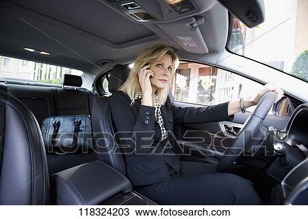 Stock Image - Businesswoman driving a car and talking on a mobile phone, Biltmore Hotel, Coral Gables, Florida, USA. Fotosearch