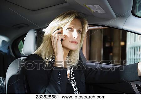 Stock Image - Businesswoman driving a car and talking on a mobile phone, Biltmore Hotel, Coral Gables, Florida, USA. Fotosearch