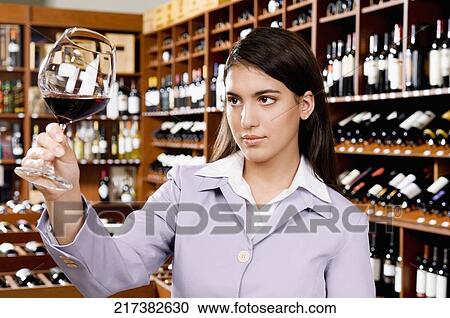 Businesswoman examining a glass of red wine View Large Photo Image Stock Image - Businesswoman examining a glass of red wine. Fotosearch
