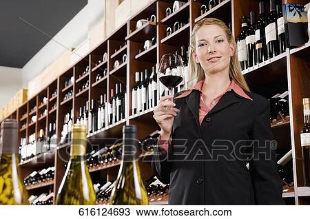 Stock Image - Businesswoman holding a glass of wine in a bar. Fotosearch