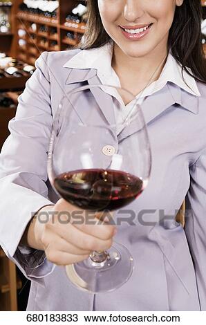 Businesswoman holding a glass of wine in a bar and smiling View Large Photo Image Stock Image - Businesswoman holding a glass of wine in a bar and smiling. Fotosearch