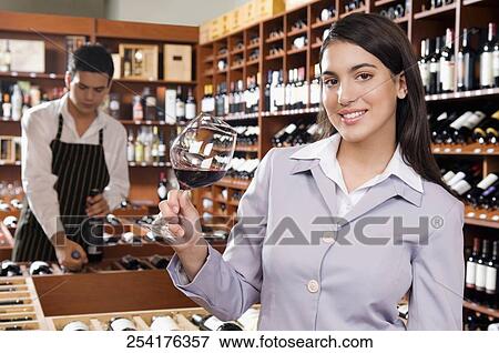 Stock Photo - Businesswoman holding a glass of wine in a bar and smiling. Fotosearch