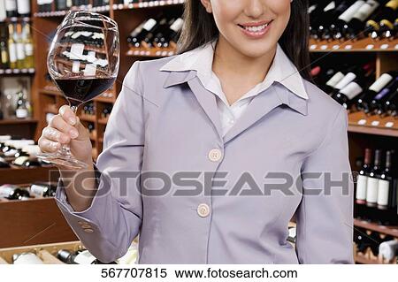 Businesswoman holding a glass of wine in a bar and smiling View Large Photo Image Stock Photography - Businesswoman holding a glass of wine in a bar and smiling. Fotosearch