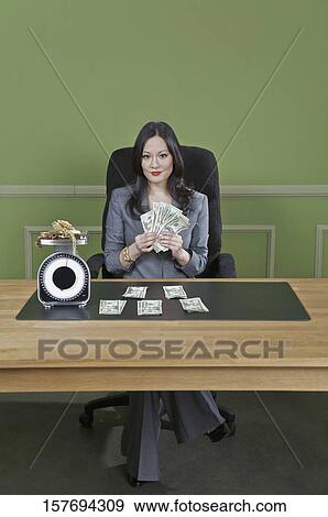 Businesswoman holding currency notes with gold jewelry on a weight scale in front of her View Large Photo Image Stock Photo - Businesswoman holding currency notes with gold jewelry on a weight scale in front of her. Fotosearch