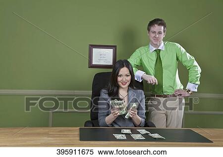 Businesswoman holding currency notes with a businessman standing beside her View Large Photo Image Stock Photography - Businesswoman holding currency notes with a businessman standing beside her. Fotosearch