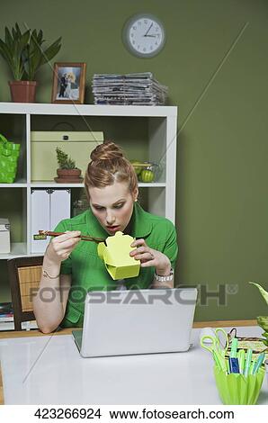 Businesswoman in the office opening packaged food View Large Photo Image Picture - Businesswoman in the office opening packaged food. Fotosearch