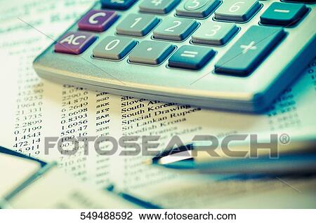 Stock Image - Calculator and a pen on a financial newspaper. Fotosearch