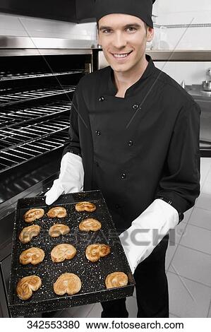 Chef holding a tray of cookies View Large Photo Image Stock Image - Chef holding a tray of cookies. Fotosearch