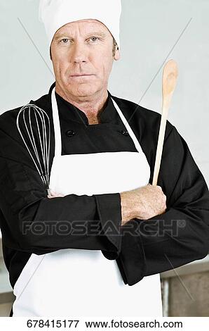 Stock Photo - Chef holding a wooden spoon and a wire whisk. Fotosearch
