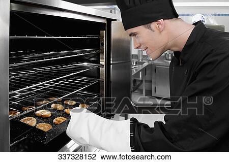 Chef taking out a tray of cookies from an oven View Large Photo Image Stock Image - Chef taking out a tray of cookies from an oven. Fotosearch