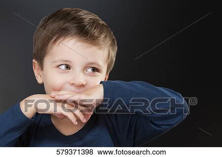 Stock Photo - Close-up of a boy covering his mouth. Fotosearch