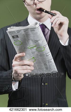 Stock Image - Close-up of a businessman marking on a newspaper. Fotosearch