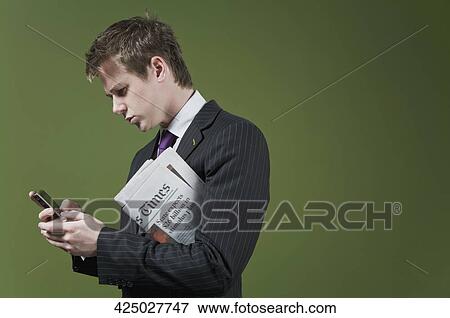 Close-up of a businessman using a mobile phone and holding a newspaper View Large Photo Image Stock Photo - Close-up of a businessman using a mobile phone and holding a newspaper. Fotosearch