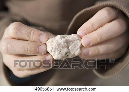 Stock Image - Close-up of a child's hands holding a stone. Fotosearch