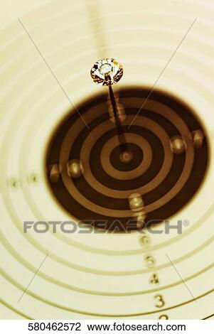 Stock Image - Close-up of a dart on a dartboard. Fotosearch