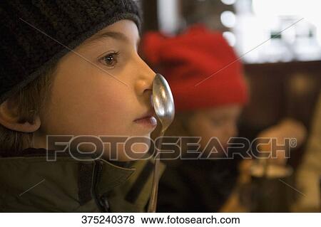 Stock Photo - Close-up of a girl with a spoon on her nose. Fotosearch