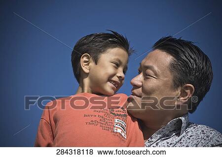 Close-up of a man carrying his son View Large Photo Image Stock Photo - Close-up of a man carrying his son. Fotosearch