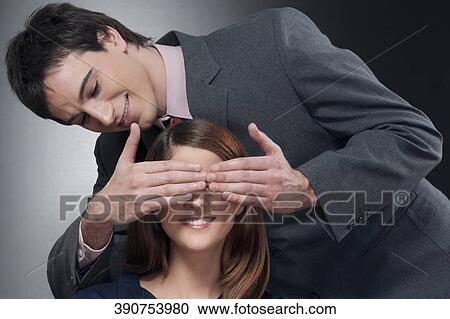Stock Image - Close-up of a man covering a woman's eyes. Fotosearch