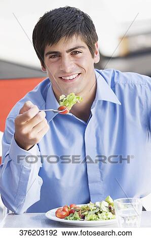Close-up of a man eating salad in a restaurant View Large Photo Image Stock Image - Close-up of a man eating salad in a restaurant. Fotosearch