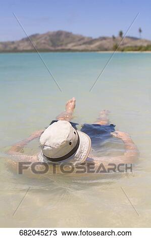 Stock Image - Close-up of a man floating on water. Fotosearch