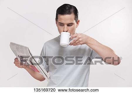 Stock Image - Close-up of a man reading a newspaper and drinking coffee. Fotosearch