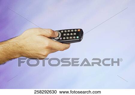 Stock Image - Close-up of a man's hand holding a remote control. Fotosearch