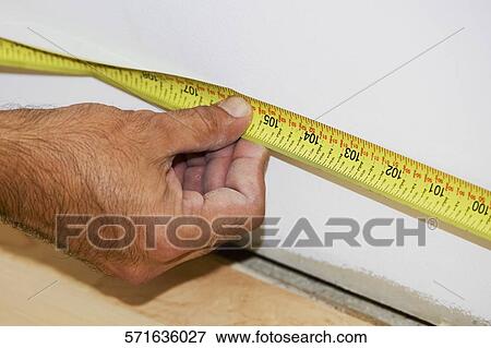 Stock Photo - Close-up of a man's hand measuring with a tape measure. Fotosearch