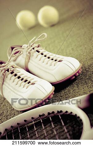 Stock Image - Close-up of a pair of shoes with a tennis racket and tennis balls. Fotosearch